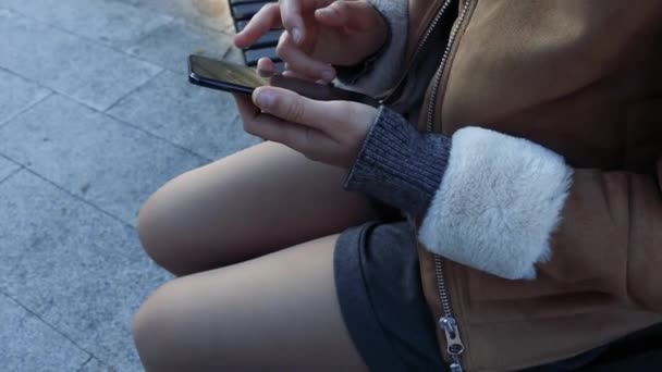 Jente som sitter i smarttelefon på gata – stockvideo