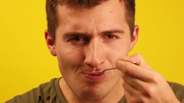 Fiatal férfi eszik gabonapelyhet tejjel, és nézd meg a kamera sárga alapon — Stock videók