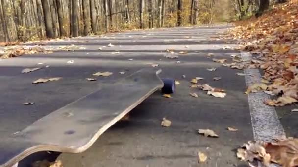 Ein einsames Longboard rollt eine Asphaltstraße hinunter — Stockvideo