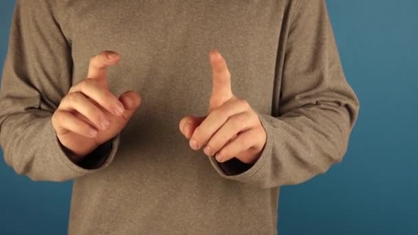 Мужчина в капюшоне с длинными рукавами делает много жестов рукой на голубом фоне . — стоковое видео