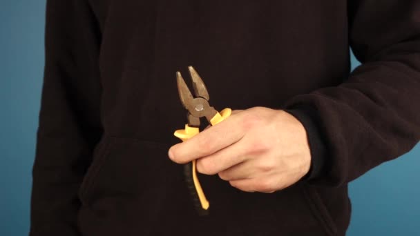 A man in a black jacket with long sleeves, holding a pair of pliers while. — Stock Video