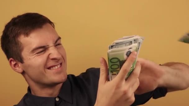Un hombre con camisa arroja dinero sobre un fondo beige — Vídeo de stock