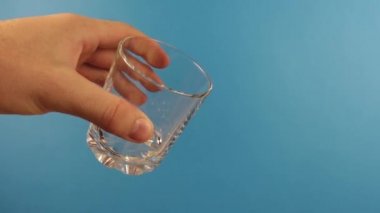 Bir adamın eli, içine kefir döküldüğü bir bardağı tutar.