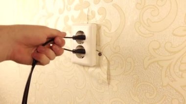 Kişi prizden iki kablo seçer. Yırtık Duvar Kağıdıyla