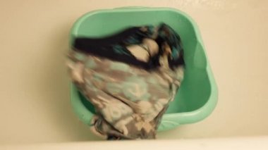 Kirli çamaşırları çamaşır leğenine atar.