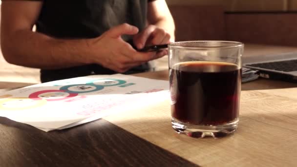 Ο άνθρωπος χρησιμοποιεί το τηλέφωνο και πίνει τσάι στο χώρο εργασίας — Αρχείο Βίντεο