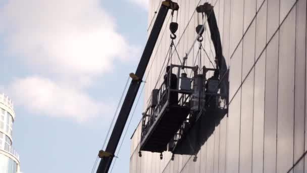 Чоловік стоїть на горизонтальній платформі, прибираючи вікна — стокове відео