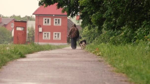 Egy férfi sétáltatja a kutyáját az esőben. — Stock videók