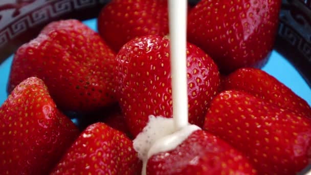 El yogur se vierte sobre las fresas en un plato — Vídeos de Stock