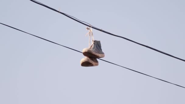 Turnschuhe hängen an Drähten gegen den blauen Himmel — Stockvideo