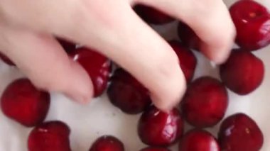 Bir adam tabakta kiraz karıştırıyor.