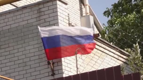 En stor rysk flagga hänger på ett vitt tegelhus — Stockvideo