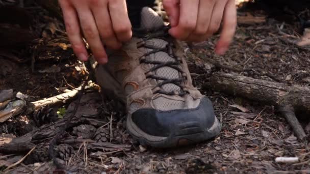 Чоловік зв'язує свої шнурки в лісі — стокове відео