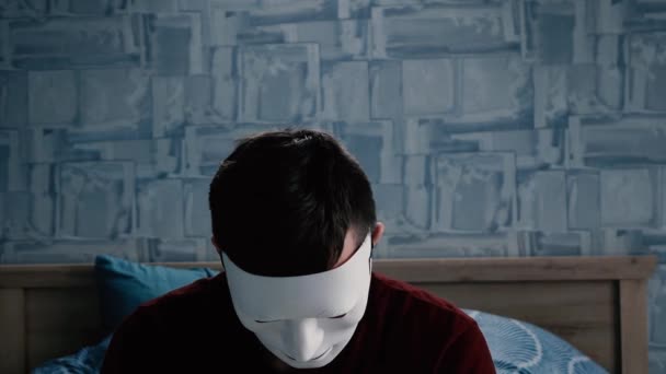 Человек в белой маске поднимает голову перед камерой — стоковое видео