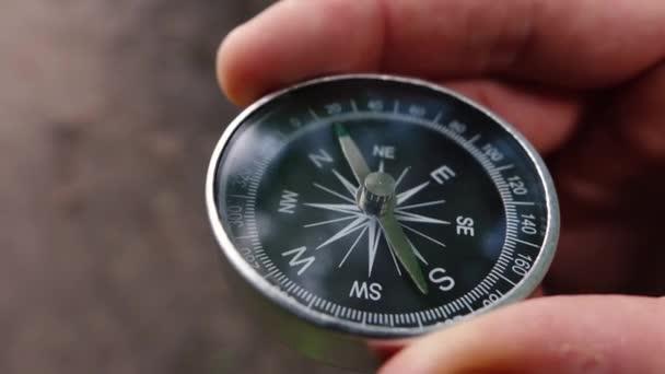 Мужчина-турист, находясь в лесу, держит в руках серебряный компас — стоковое видео