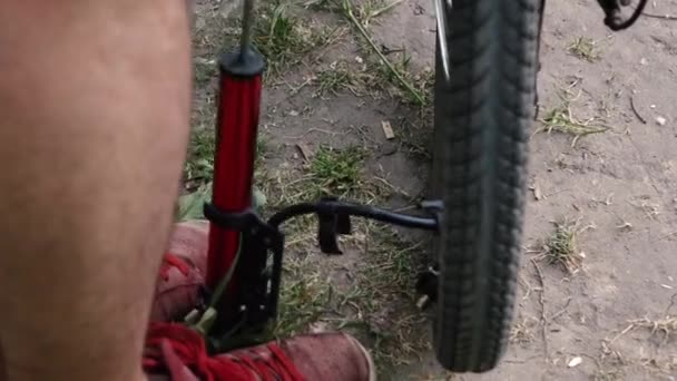 Чоловік накачує велосипедне колесо. поломка на дорозі — стокове відео