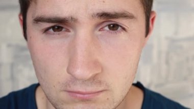 Uykulu ve dikkatsiz bir adam kameraya bakar.