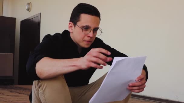 Un homme avec des lunettes étudie le document avec le rapport. assis dans la rue — Video