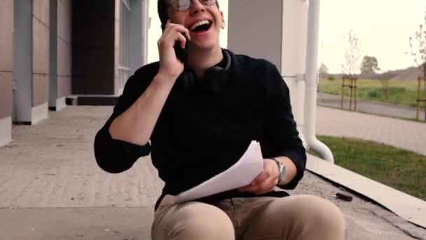Веселый бизнесмен разговаривает по телефону и сортирует бумаги — стоковое видео