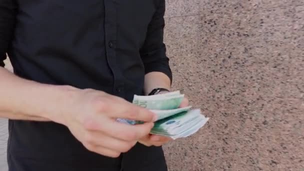 Young businessman walks down the street and counts money close up — Stock Video