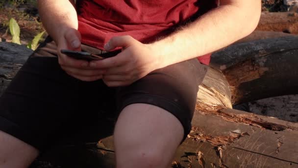 Ένας άντρας χρησιμοποιεί ένα τηλέφωνο στο δάσος. — Αρχείο Βίντεο