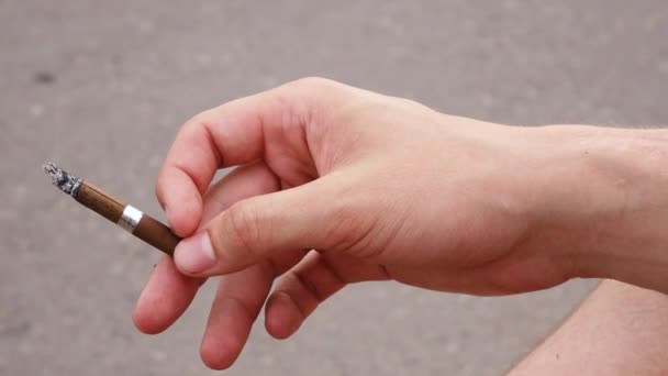 Um homem dispara cinzas de um cigarro enquanto na rua. — Vídeo de Stock