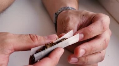 Bir adam ev yapımı bir sigara sarar.