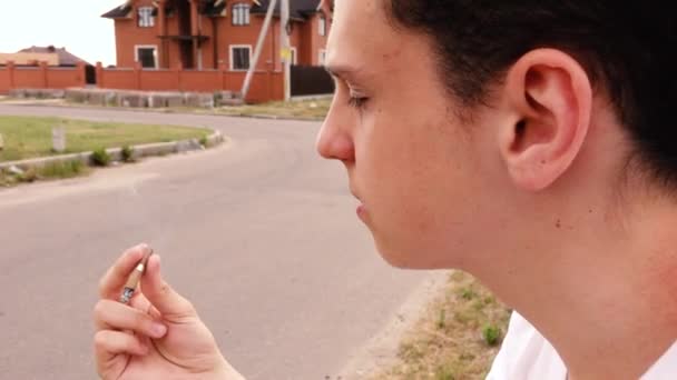 Un homme avec une cigarette assis dans la rue — Video