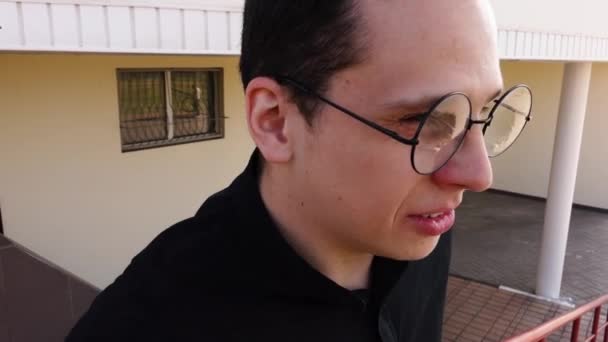 Sagt ein Mann mit runder Brille, der auf der Straße in die Kamera schaut — Stockvideo