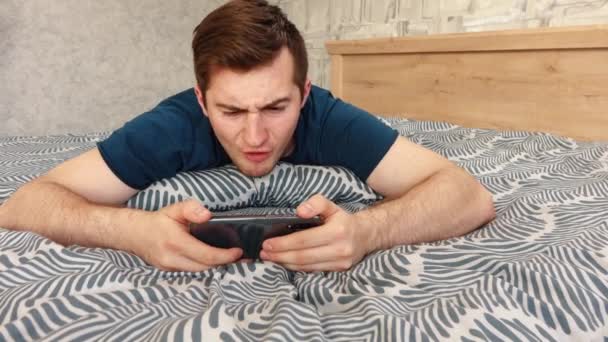 Gars joue le téléphone et se met en colère couché sur le lit — Video