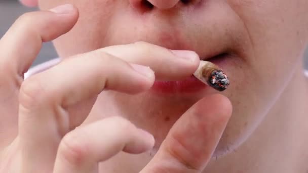 Mann raucht Zigarette, während er vor der Kamera steht — Stockvideo