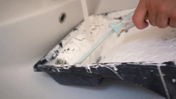 Constructeur lave le rouleau avec un seau de peinture blanche — Video