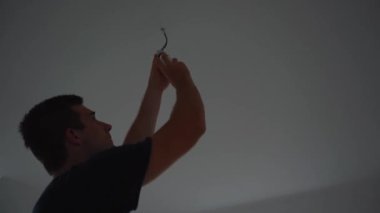 Adam bir ampulü vidalıyor ve yanıyor.