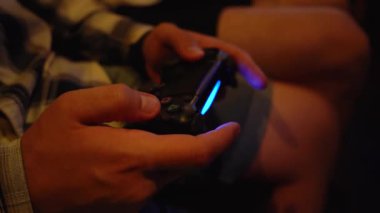 Bir adam oyun konsolu oynamak için joystick kullanır.