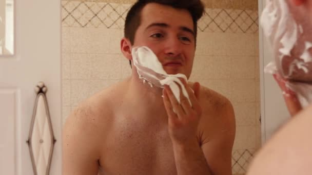 Homem esfrega seu rosto com espuma no banheiro . — Vídeo de Stock