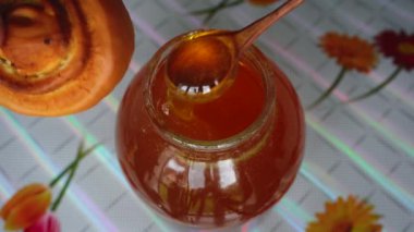 Adam büyük bir kavanozdan bir somuna bal sürer.