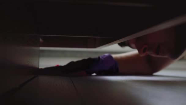 Мужчина убирается под кроватью. концепция порядка и чистоты — стоковое видео