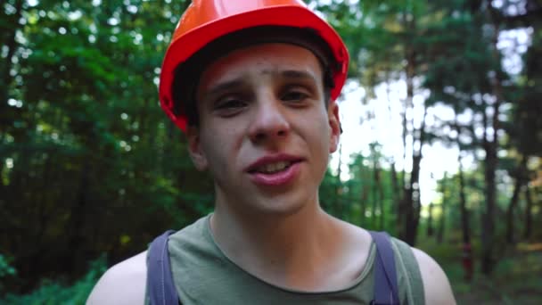 Hombre con un sombrero duro habla a la cámara mientras está de pie en el bosque — Vídeo de stock
