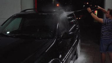 Adam arabanın köpüğünü yıkar.