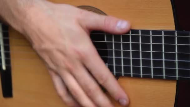 Hombre toca una guitarra clásica mientras está sentado en casa — Vídeo de stock