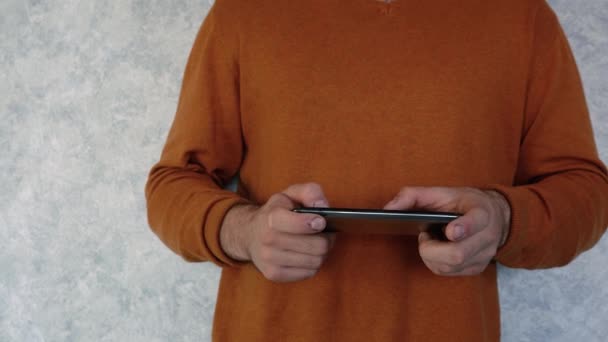 Man i orange t-shirt använder en telefon — Stockvideo