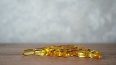 Balık yağı kapsülleri ahşap bir arka planda yatıyor.