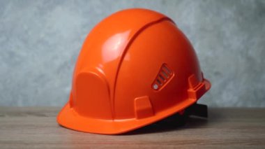 Tahta bir masanın üzerinde yan yatan turuncu bir kask. kamera yakınlaştır