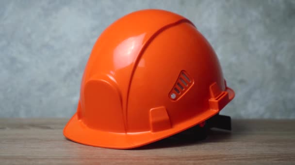 Un casco naranja acostado de lado sobre una mesa de madera. zoom de cámara — Vídeo de stock