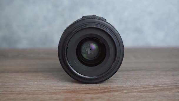 Zwarte lens van de camera ligt op een houten tafel — Stockvideo