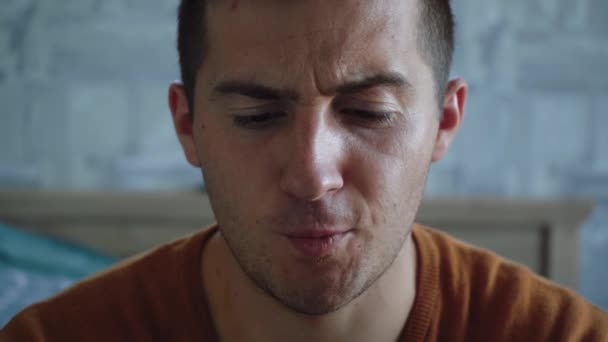 Férfi vonagló arc ül egy szobában — Stock videók
