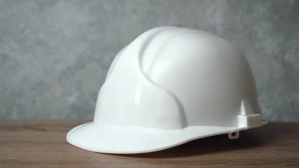 白色的工人头盔躺在一张木制桌子上 — 图库视频影像