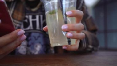 Kız sokakta bir masada otururken limonata içiyor.