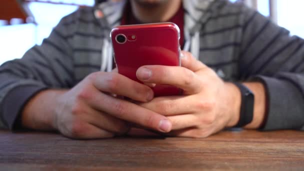 Uomo utilizza un telefono rosso mentre seduto a un tavolo — Video Stock