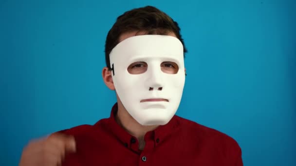 Mann entfernt eine anonyme Maske auf blauem Hintergrund — Stockvideo